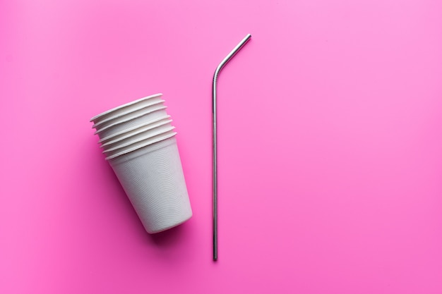 Flat lay of sustainable products, paper glass and stainless straw on pink