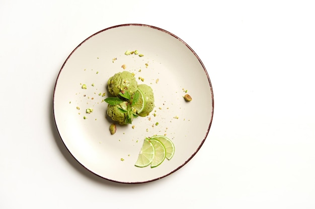 Disposizione piatta tre palline di sorbetto di gelato al pistacchio e lime su un piatto isolato su sfondo bianco con spazio pubblicitario per la copia