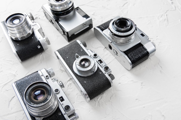 Flat lay of three old vintage photo cameras on the white background with free space for text mock up