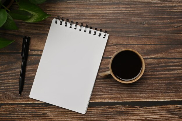 Flat lay Top view blank notepad pen and cup of coffee on wooden table