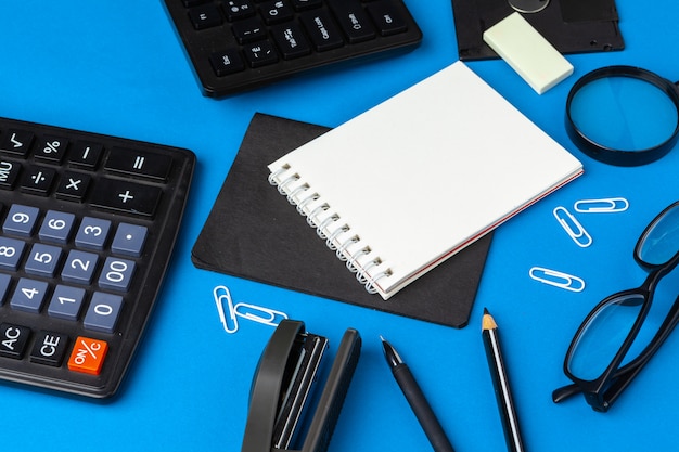 Flat lay, top view of blue office table desk. Workspace with blank note book,  office supplies 