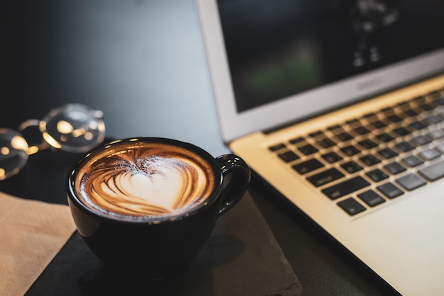 Flat lay top view of laptop eyeglasses and cup of coffee on the
table simple workspace or coffee break in morning