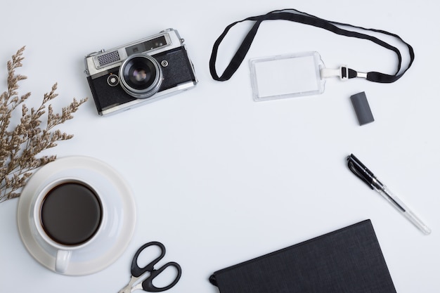 Flat lay, top view modern office table desk. book,camera ,coffee,nametag and pen on white background