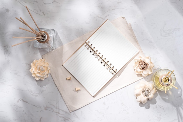 Flat lay, top view of open notebook with aroma bottle glass and wooden sticks on the table