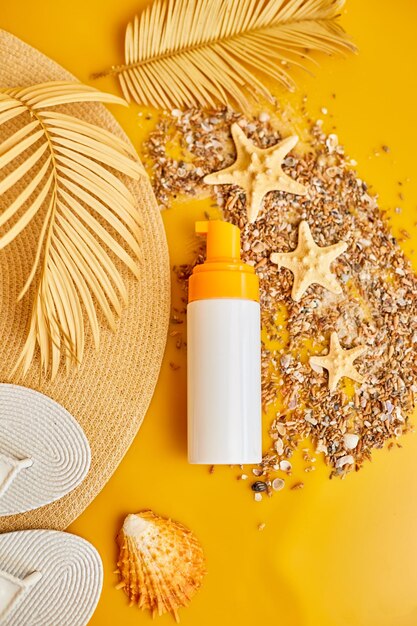 Flat lay top view sunscreen tube mockup with shells sand yellow background summer vacations and spf uvprotecting skin care concept