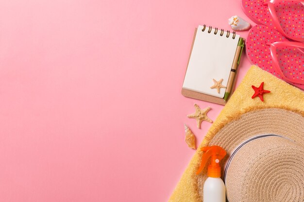 Lay piatto, vista dall'alto concetto di viaggio. accessori estivi con carta per appunti e conchiglia su sfondo rosa.