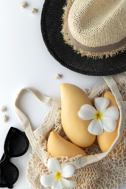 Flat lay top view traveler accessories, fruits, straw hat on white background with empty space for text