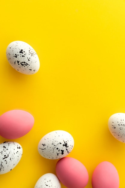 Flat lay top view of white and pink eggs with minimal designs on yellow background