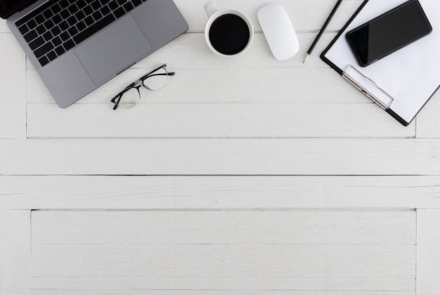 Photo flat lay, top view wooden office desk. workspace with blank clipboard, laptop, mouse computer, smartphone, eye glasses, coffee cup office supplies