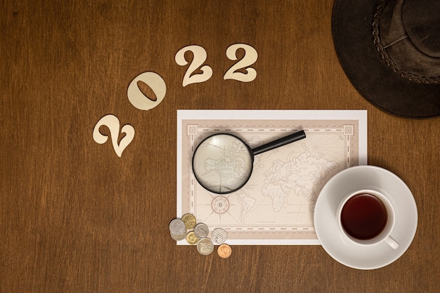 Flat lay travel composition with numbers 2022 and world map on wooden background, travel concept.