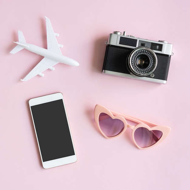 flat lay of travel items and mobile phone on pink desk. summer, holiday and planning travel concepts