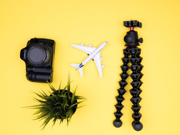 Flat lay of traveler kit on yellow background with camera and tripod