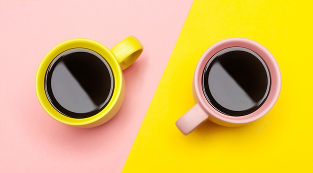 Flat lay of a two coffee cups with pink and yellow