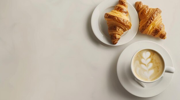 2杯のカプチーノと2杯のクロワッサンを白いテーブルの上に置く