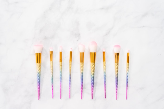 Flat lay. Unicorn color makeup brushes on a marble background.