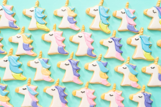 Flat lay. Unicorn sugar cookies decorated with royal icing and food glitter on a blue background.