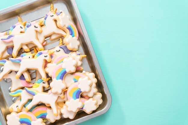 Flat lay. Unicorn sugar cookies decorated with royal icing and food glitter on a blue background.