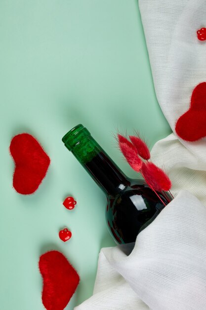 Flat lay of Valentines day greeting card with red wine bottle and hearts on blue