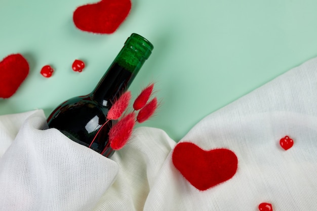 Flat lay of Valentines day greeting card with red wine bottle and hearts on blue