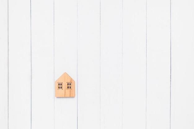 Foto flat lay van het houten huismodel op witte tafel achtergrond