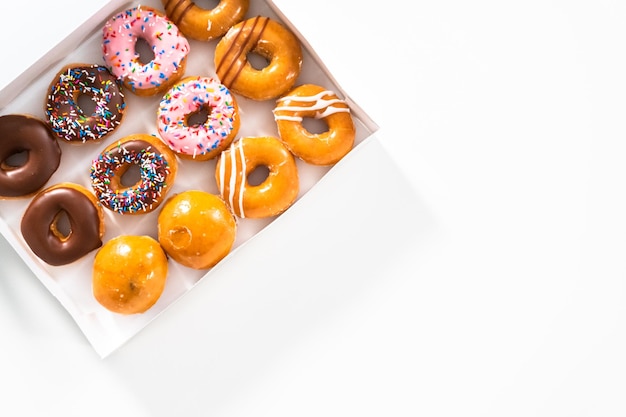 Flat lay Variety of storebought doughnuts in a white paper box