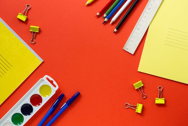 Flat lay of various school supplies on a red background. Space for text