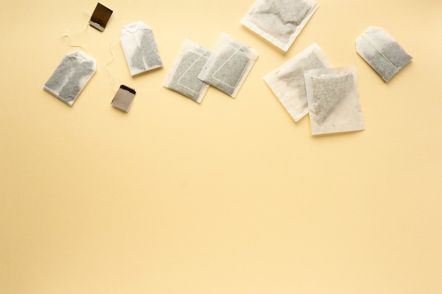 Flat lay of various tea bags on beige background, space for text.