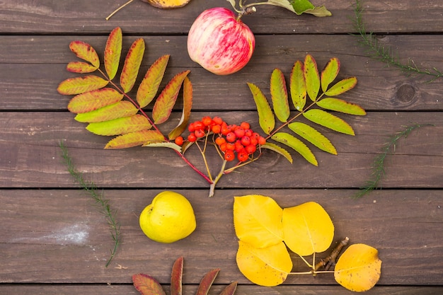 Flat lay view of autumn leaves and and fruit on brown wooden table