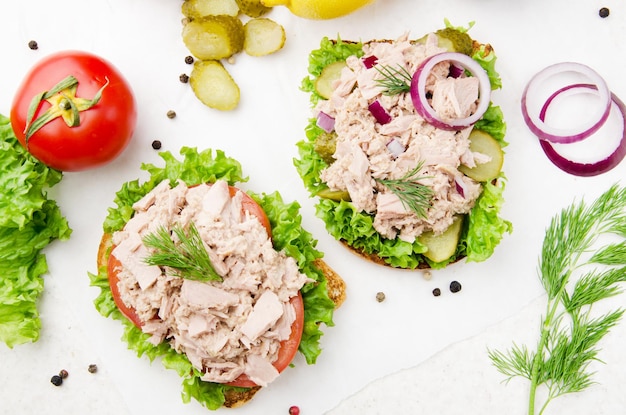 Flat lay view at Tuna sandwiches with lettuce tomatoes pickles and onions on parchment paper