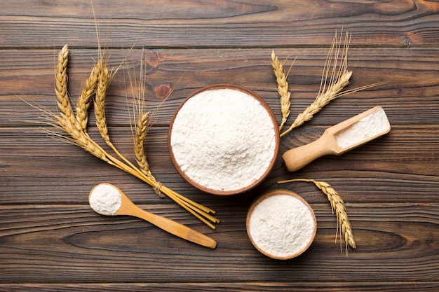 Flat lay of Wheat flour in wooden bowl with wheat spikelets on colored background world wheat crisis