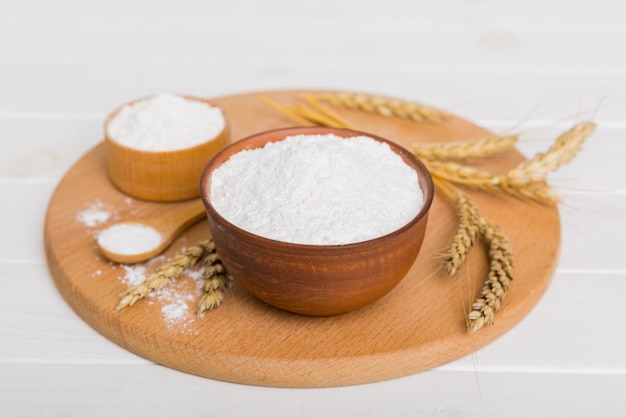 Flat lay of Wheat flour in wooden bowl with wheat spikelets on colored background world wheat crisis