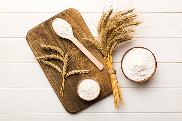 Flat lay of Wheat flour in wooden bowl with wheat spikelets on colored background world wheat crisis