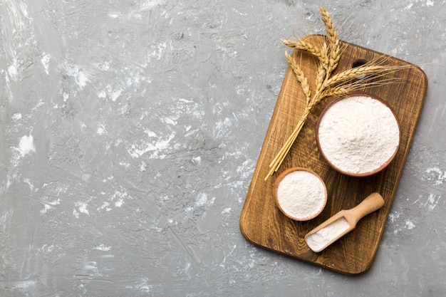 Flat lay of Wheat flour in wooden bowl with wheat spikelets on colored background world wheat crisis