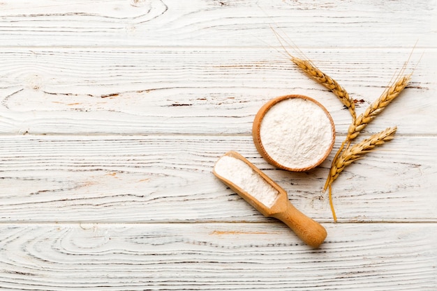 Flat lay of wheat flour in wooden bowl with wheat spikelets on
colored background world wheat crisis