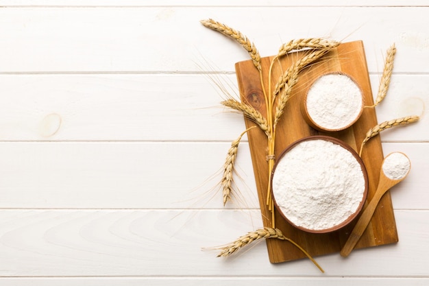 Flat lay of Wheat flour in wooden bowl with wheat spikelets on colored background world wheat crisis