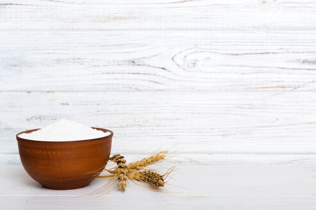 Flat lay of Wheat flour in wooden bowl with wheat spikelets on colored background world wheat crisis