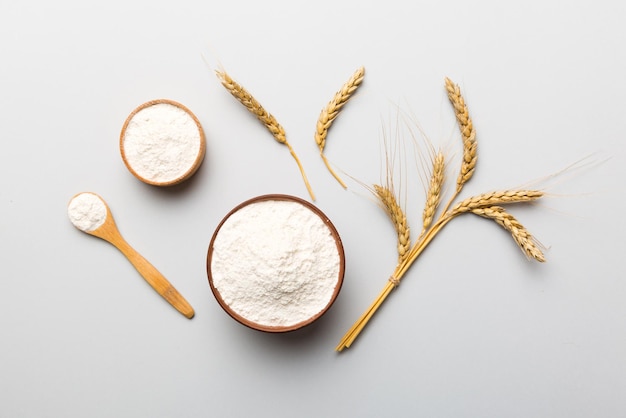 Flat lay of Wheat flour in wooden bowl with wheat spikelets on colored background world wheat crisis