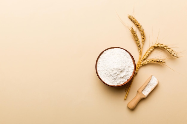 Flat lay of Wheat flour in wooden bowl with wheat spikelets on colored background world wheat crisis