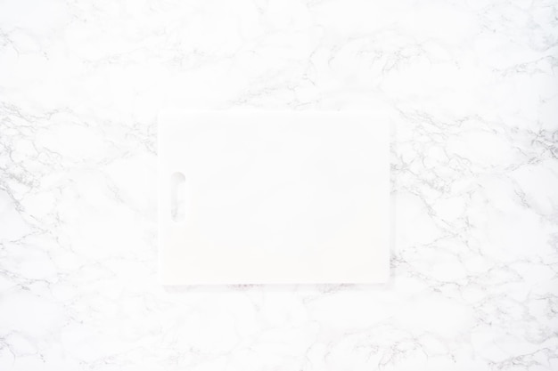 Flat lay. White cutting board on a marble background.