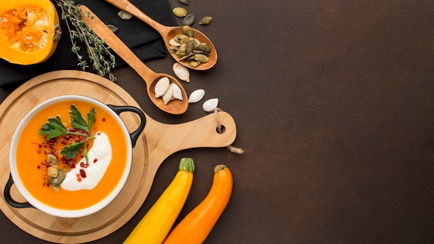 Photo flat lay of winter squash soup in bowl on chopping board with copy space