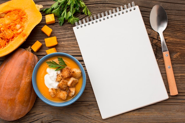 Flat lay of winter squash soup in bowl with notebook