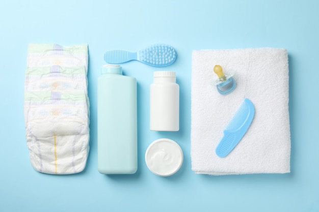 Flat lay with baby hygiene accessories on blue wall