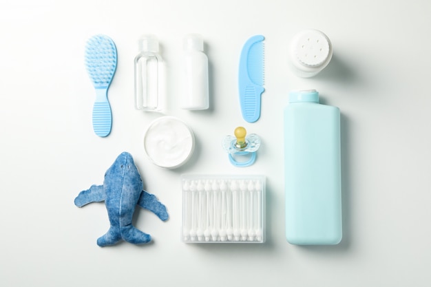 Flat lay with baby hygiene accessories on white wall