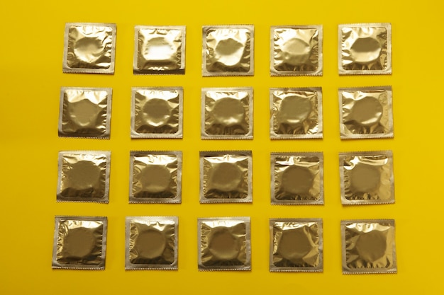 Flat lay with blank condoms on yellow surface