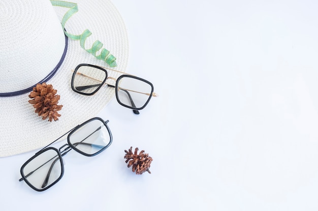 Flat lay with blank copy space. two glasses, a pine flower and a hat on a white background. minimalist concept idea