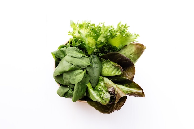 Flat lay with bowl of fresh green salad leaves of spinach and lettuce, romaine and basil. Healthy vegetarian eating concept.