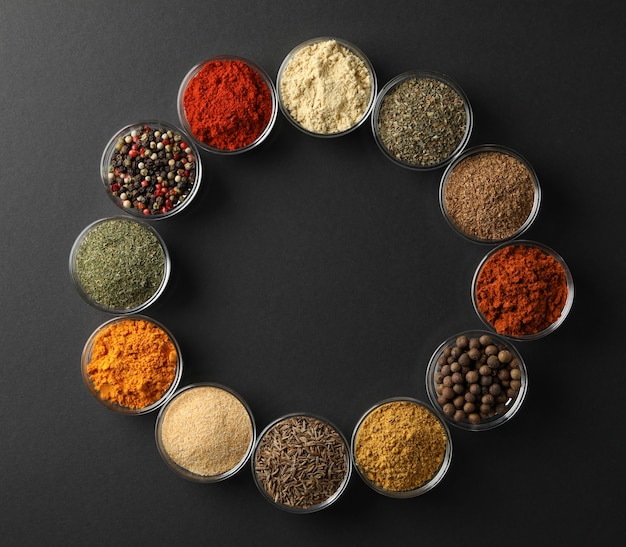 Flat lay with bowls of spices on black background, space for text