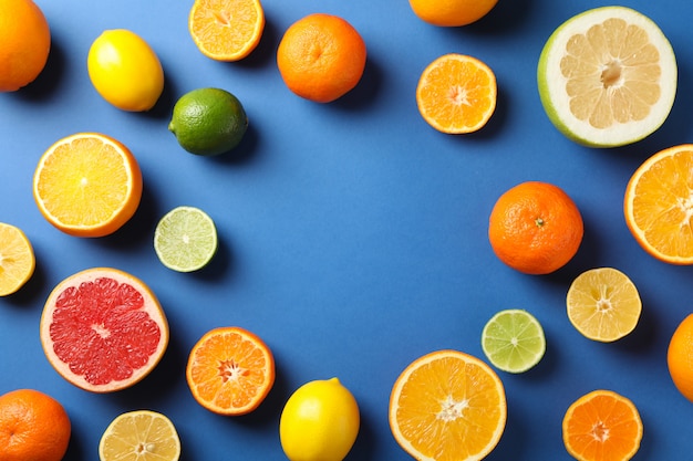 Flat lay with citrus fruits on blue background, space for text