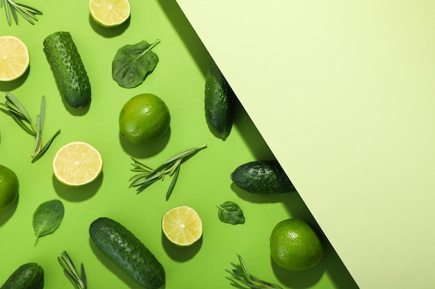 Flat lay with cucumbers limes basil and rosemary on two tone background