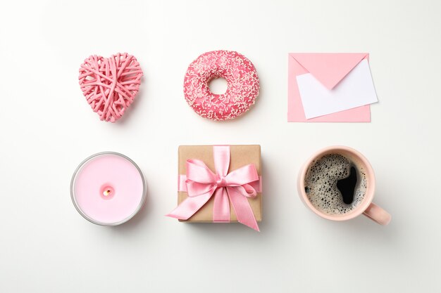 Flat lay with cup of coffee, donut, gift, candle, envelope and heart on white background, top view